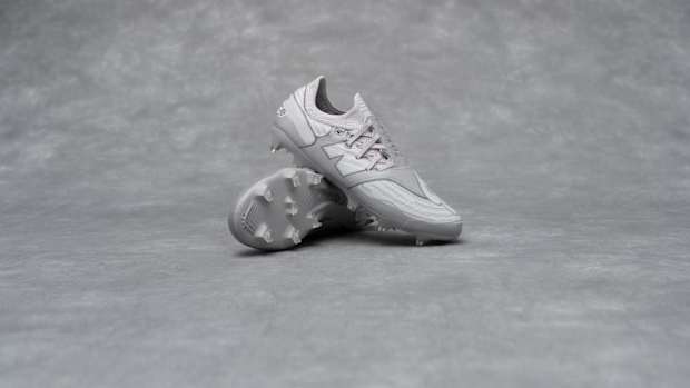 Side view of grey New Balance soccer cleats.